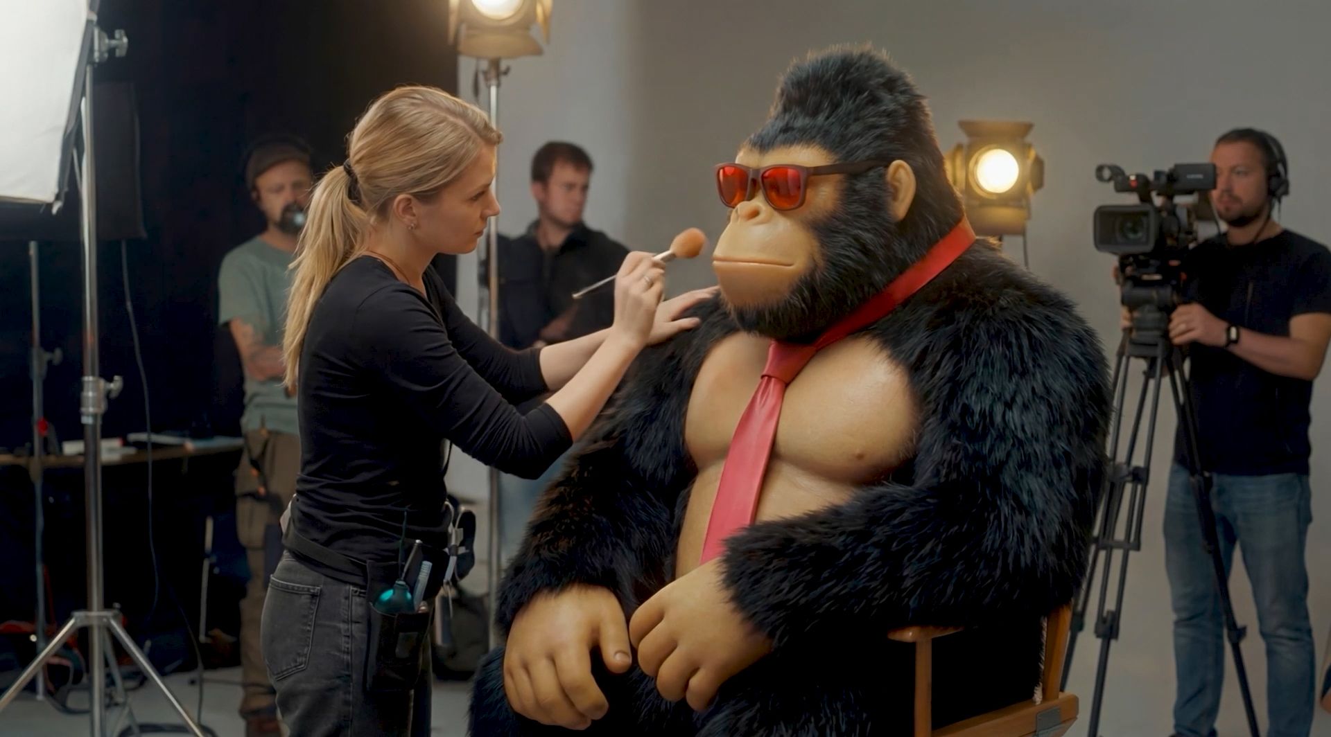 The FEG gorilla in sunglasses and a red tie getting makeup on a film set